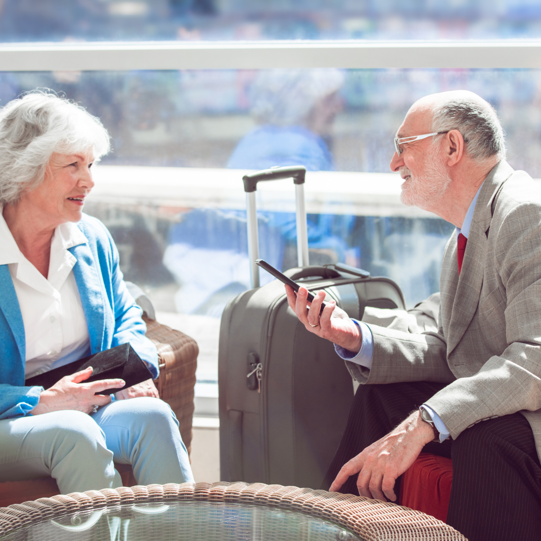 A photo of elderly couple sitting by the airport waiting area with some luggages